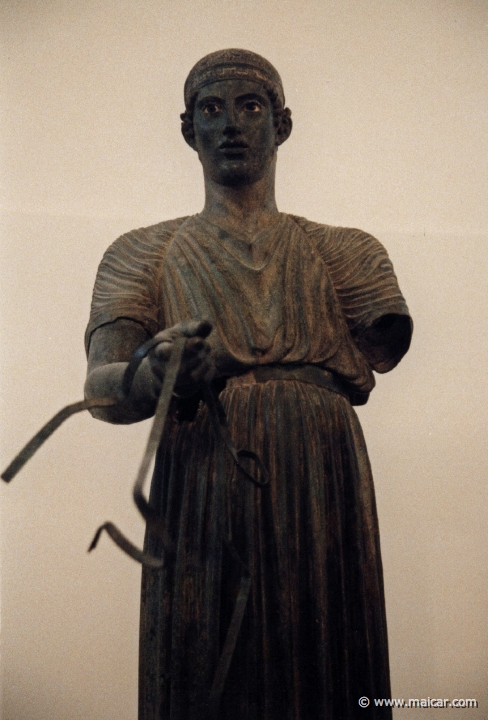 6010.jpg - 6010: Bronze statue of a charioteer belonging to a quadriga. Dedication of the Syracusean Polyzalos, brother of the tyrants Gelo and Hiero. Masterpiece of an unknown artist (about 478 BC). Archaeological Museum, Delphi.