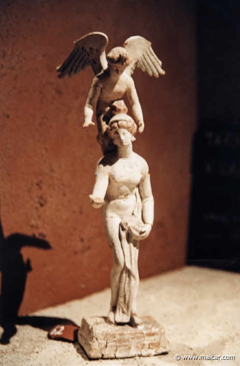 6916.jpg - 6916: Terrakotafigurin. Den nakna Afrodite med den bevingade Eros. Figurinen föreställer en populär antik grekisk lek, efedrismos, i vilken förloraren i en bollsport fick bära vinnaren på ryggen, ofta med vinnarens händer för ögonen. 325-275 f.Kr. (inv. nr. 4080). Medelhavsmuseet, Stockholm.