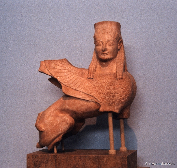 6127.jpg - 6127: Statue of a Sphinx. Pentelic marble. Found in Spata (or Spaca?), Attica. One of the earliest known archaic sphinxes. It was once used as finial (?) of a grave stele. About 570 BC. National Archaeological Museum, Athens.
