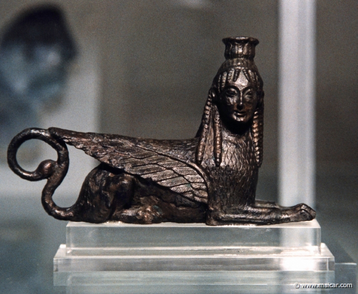 6730.jpg - 6730: Sphinx. Bronze jewelry from the sanctuary, dating from the geometric period up to Roman period. Archaeological Museum, Olympia.