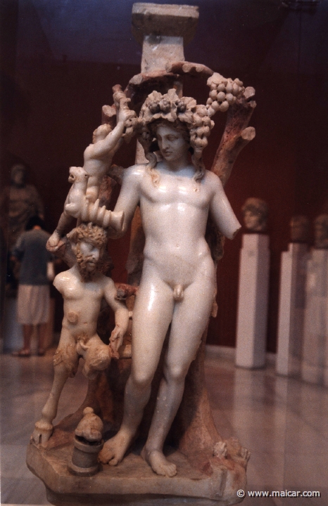 6208.jpg - 6208: Table-support. Young Dionysos crowned with an ivy and wine wreath, holds in his right hand a rhyton (ritual vase) ending in a half-panther. Goat shanked (? shaped?), horned god Pan stands under Dionysos’ right arm who holds a lagabolon (a staff for flinging at hares). A small Satyr has climbed upon the vine branch. Product of an Asia Minor workshop AD 170. National Archaeological Museum, Athens.